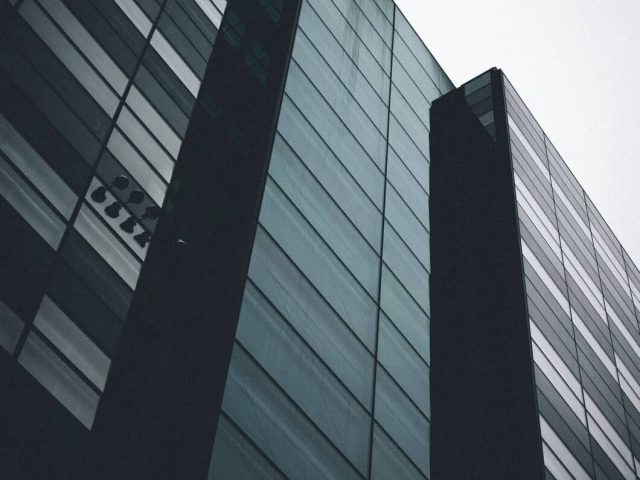 vertical-low-angle-shot-black-building-with-mirror-windows-clear-sky_181624-5129.jpg